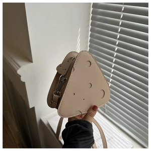 Dettaglio di una borsa a tracolla beige a forma di formaggio con fori circolari creativi