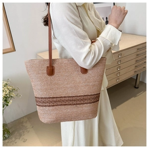 Detail view of woven straw tote bag with brown leather straps and textured pattern