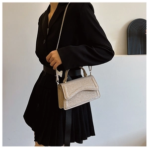 Detail view of a silver shimmering handbag with asymmetrical flap and chain strap for evening