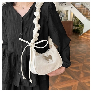 Detail of the large butterfly bow decoration and metallic logo on the pleated shoulder bag