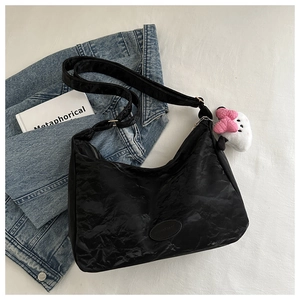 Détail du sac cabas noir froissé avec une breloque en peluche et un nœud rose