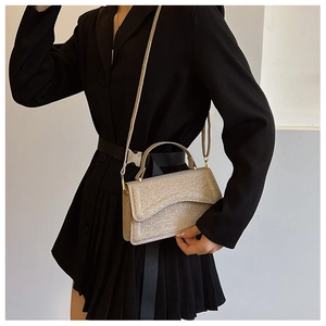 Detail view of champagne gold glitter crossbody bag worn with a black outfit