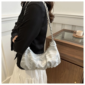Silver metallic pleated underarm bag with braided handle shown on model's shoulder
