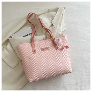 Detailed view of pink quilted tote bag with fashion tag and fuzzy charm on blazer