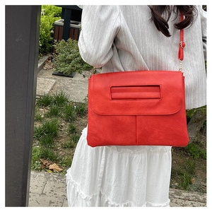 Vue latérale du grand sac à bandoulière rouge avec texture cuir et sangle réglable