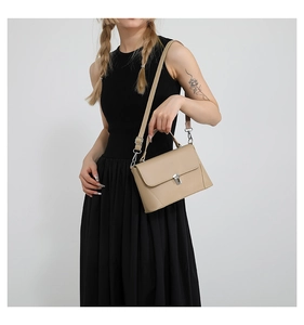 Detail view of smooth beige leather shoulder bag with silver square buckle and top handle