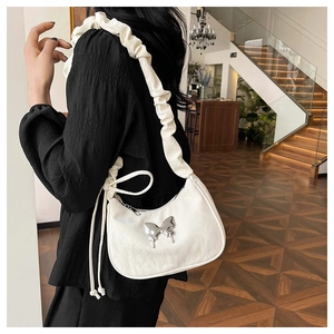 Detailed view of white crescent bag with silver butterfly accent and ruffled strap