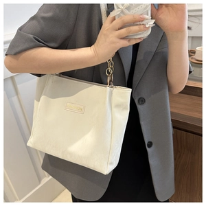 Dettaglio borsa tote color crema con tracolla a catena dorata e patch FASHION
