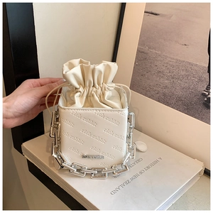 Detail of white leather bucket bag featuring rich rabbit embossing and chunky silver chain