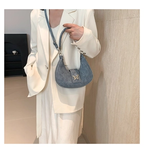 Dettaglio della borsa a mezzaluna blu denim con chiusura a farfalla dorata vintage