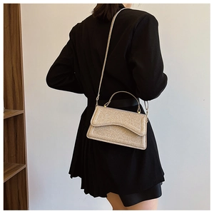 Sparkling champagne gold sequined evening handbag shown on a model in black attire