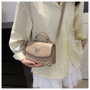 Detail of beige chevron quilted crossbody bag with silver butterfly metal clasp lock