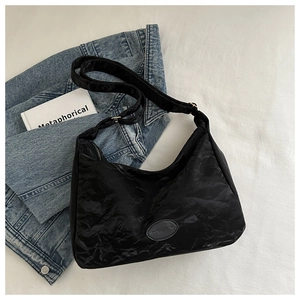 Détail du sac fourre-tout noir plissé avec bandoulière réglable sur fond de lin et de jean