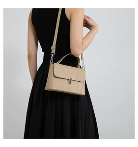 Close-up of beige leather crossbody bag with silver buckle and adjustable shoulder strap