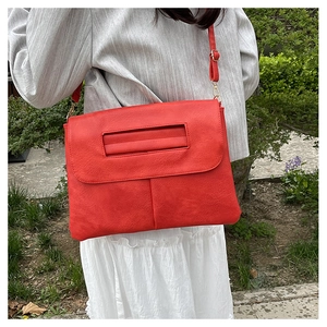 Sac bandoulière rouge avec texture litchi et poignée creuse porté par un mannequin