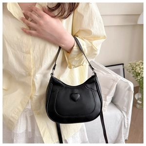Detail of a black saddle bag featuring a 3D heart design and slim shoulder strap