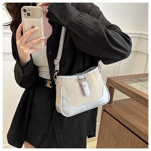 Detail of beige canvas and silver leather handbag with adjustable strap and metal buckle
