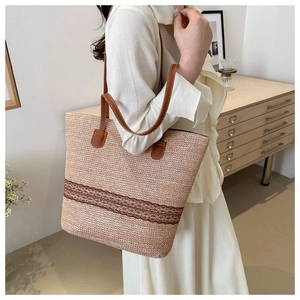 Detail of large woven tote bag with brown embroidery trim and leather shoulder strap