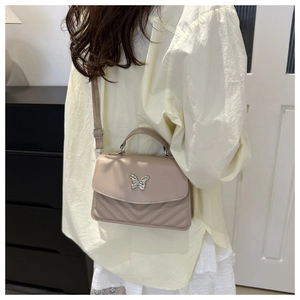 Close-up of quilted coffee-colored crossbody bag featuring a silver butterfly buckle clasp