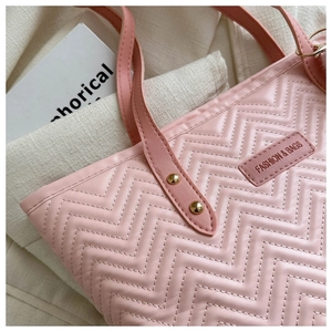 Close-up of pink tote bag with chevron quilting, gold rivets, and fashion brand label