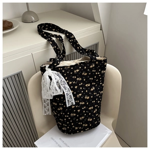 Detailed shot of black floral tote bag with lace bow on a minimalist cream chair