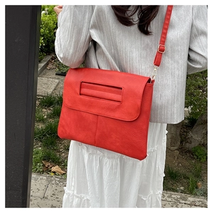 Détail d'un sac bandoulière en cuir rouge avec boucle dorée et bandoulière réglable