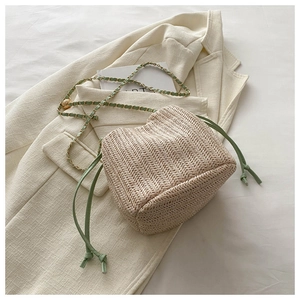 Detail of straw bucket bag with green leather drawstring and metal chain strap