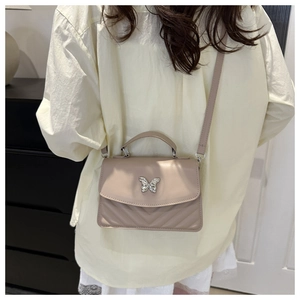 Detail of nude pink crossbody bag with silver butterfly clasp and V-quilted texture