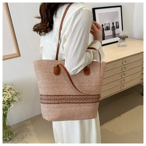 Detailed view of woven straw tote bag with brown lace trim and leather shoulder strap
