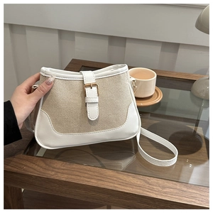 Detail of canvas and leather crossbody bag with gold metal buckle and leather strap