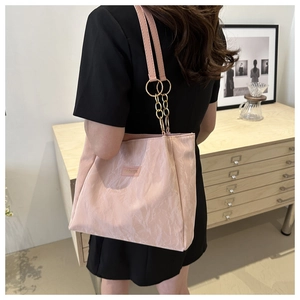 Dettaglio borsa tote rosa con tracolla a catena dorata e materiale effetto marmo
