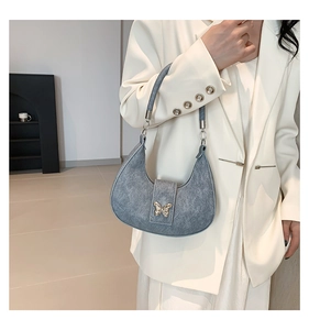 Détail du sac à bandoulière texture denim avec boucle papillon dorée élégante
