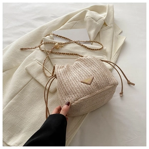 Detail of woven straw bucket bag with leather chain strap and drawstring closure