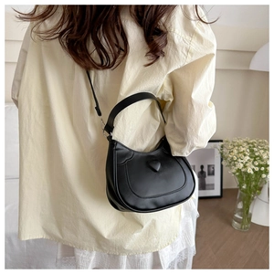 Detail of a black PU leather underarm bag with a 3D heart design on a female model