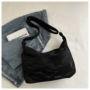 Détail du sac hobo noir style nuage avec texture plissée et finitions dorées
