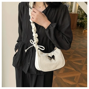 Detail of white pleated shoulder bag featuring a sleek black butterfly metal logo accent