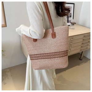 Detail of hand-woven straw tote bag with brown lace trim and slim shoulder straps