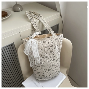 Detail of floral tote bag with lace bow accent on textured fabric and vintage finish