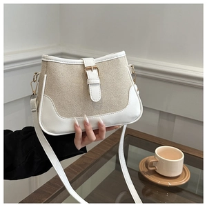 Detail of minimalist canvas crossbody bag with white faux leather trim and gold buckle