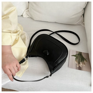 Detail of black crescent moon bag with 3D heart decoration and adjustable leather strap