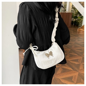 Detail of white pleated shoulder bag with metallic butterfly buckle and bow strap
