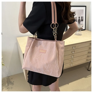 Dettaglio della borsa tote rosa con trama pieghettata e tracolla a catena dorata