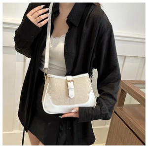 Close-up of minimalist canvas crossbody bag with white faux leather trim and gold buckle