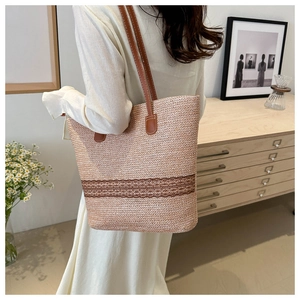 Detail of woven straw tote bag with brown embroidered lace and leather shoulder strap