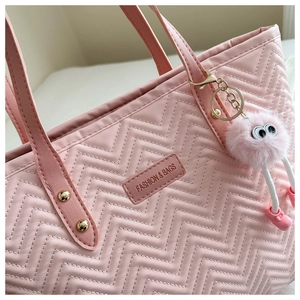 Detailed view of pink quilted tote bag with wavy patterns and cute monster charm