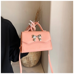 Detail of peach pink crossbody bag with cross-grain leather and silver bow ornament