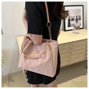 Dettaglio della borsa tote rosa chiaro con trama marmorea e catena dorata a tracolla