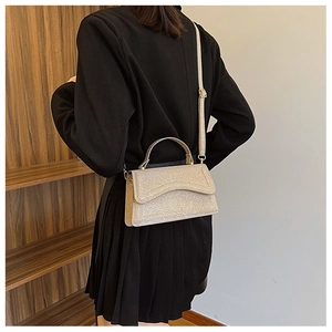 Champagne gold sequin handbag with wave-cut flap shown from a stylish back-view angle