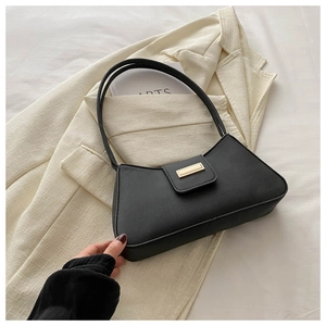 Minimalist black baguette bag on beige blazer featuring elegant gold rectangular clasp