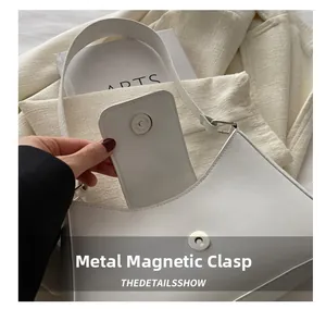 Close-up of the magnetic hardware snap closure on a white PU leather baguette bag